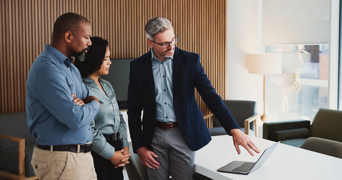 Business team in an office reviewing documents together around a laptop